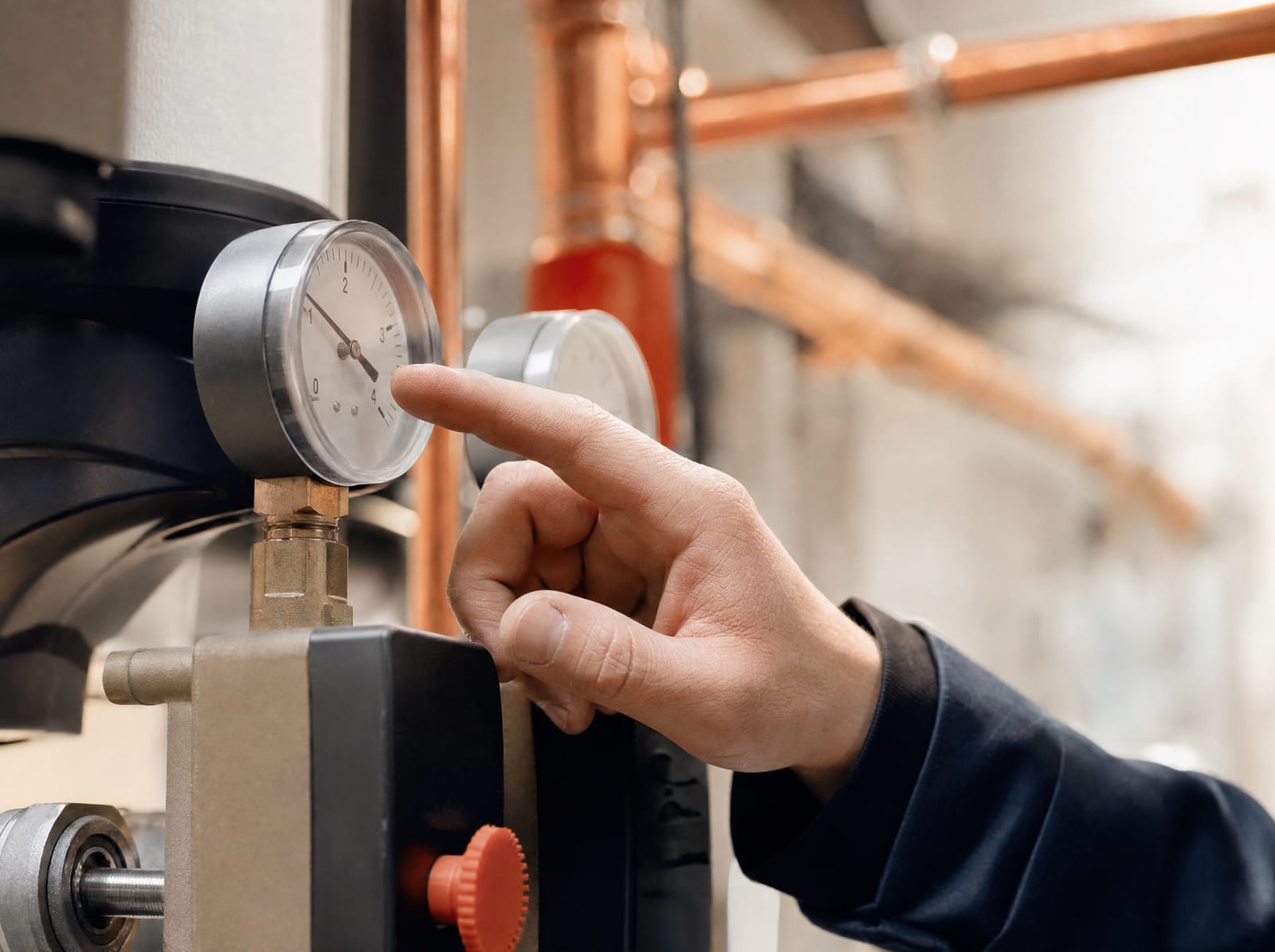 Technician reading pressure gauges on a heating system in a plant room
