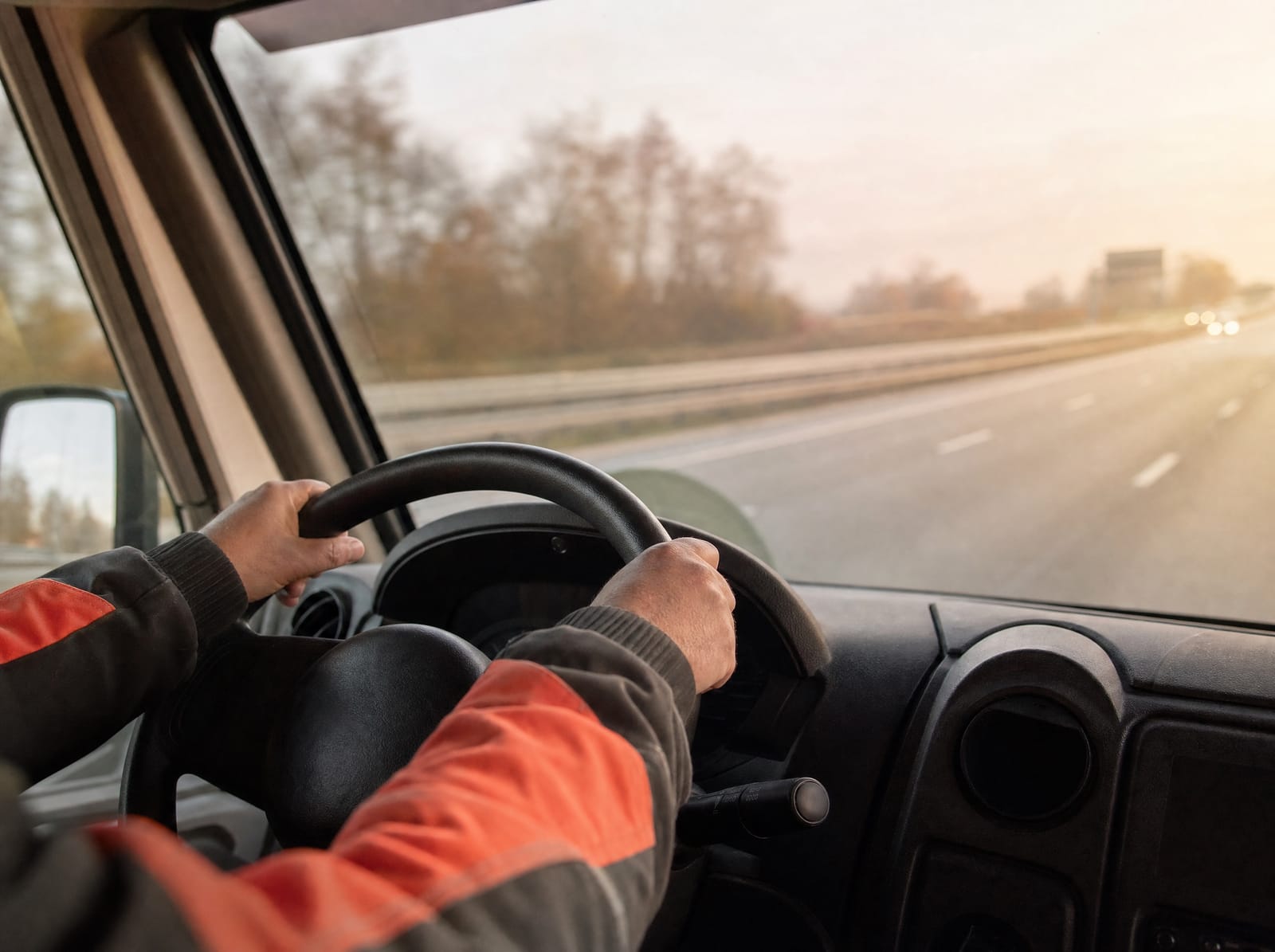 Driver’s hands on the wheel of a service van on a Danish motorway in morning light