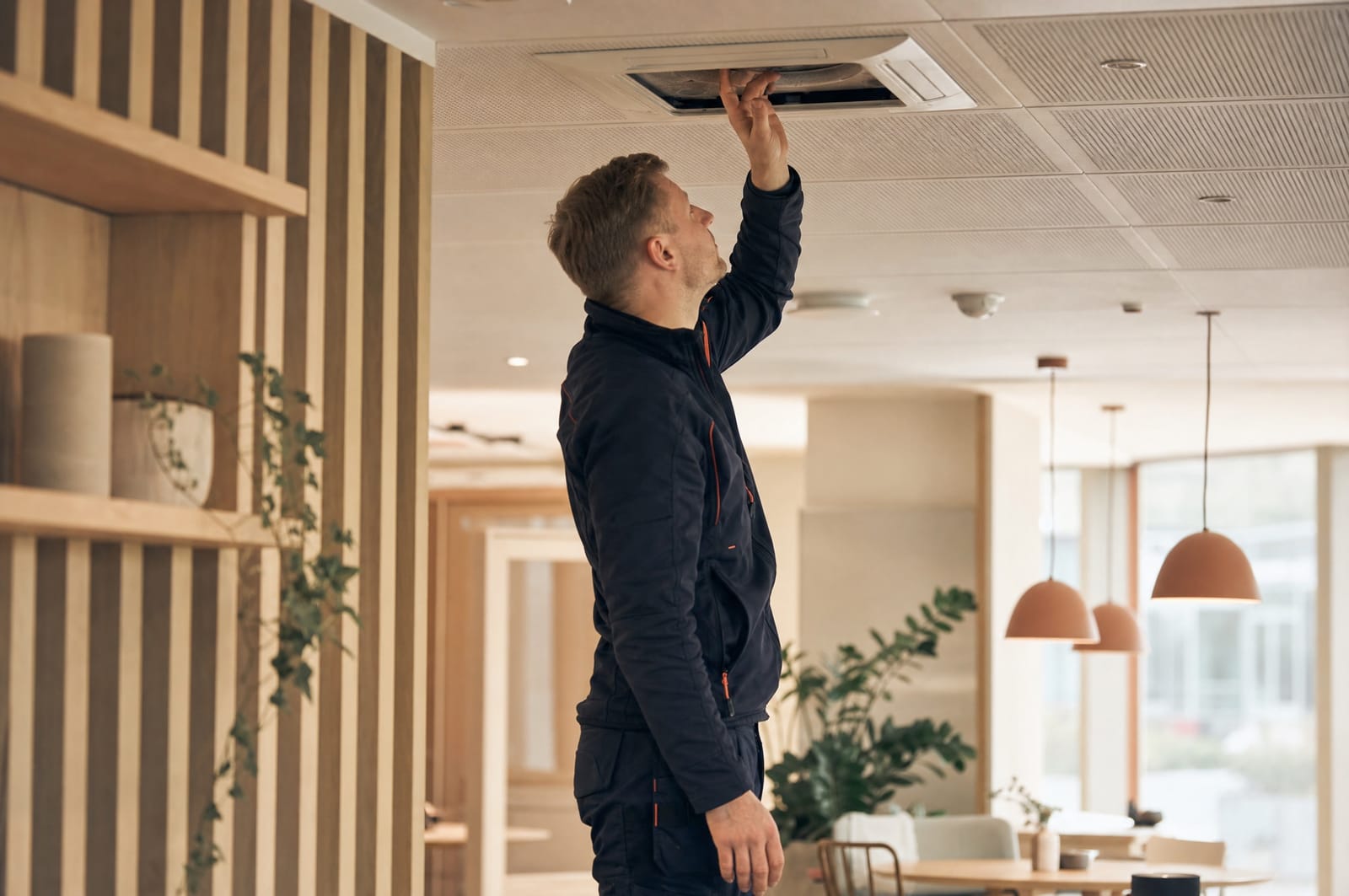 Service technician carrying out a scheduled inspection of a ventilation system in a modern office